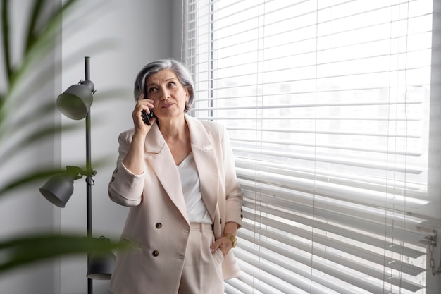 Donna anziana del tiro medio che parla al telefono