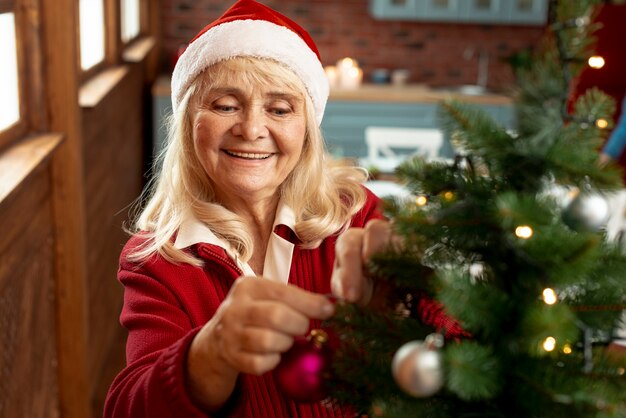 Donna anziana dell'angolo alto che decora l'albero di Natale