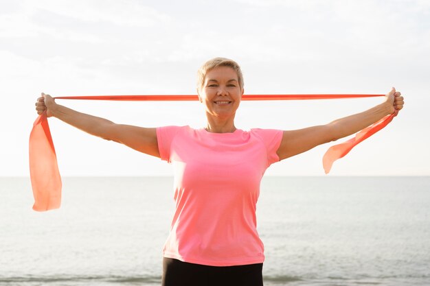 Donna anziana di smiley con corda elastica sulla spiaggia