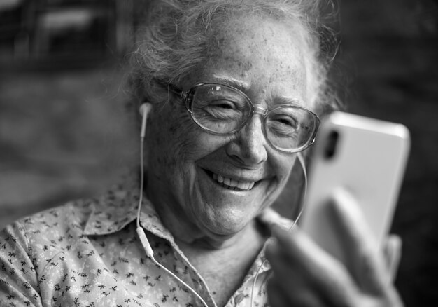 Donna anziana felice che gioca al telefono