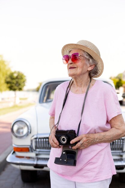 Donna anziana felice che tiene una macchina fotografica durante il viaggio