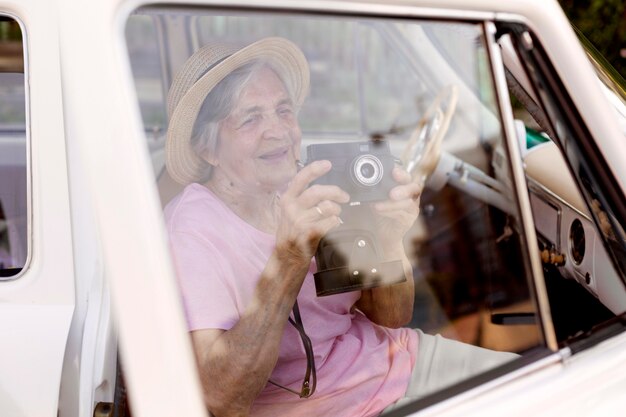 Donna anziana felice che tiene una macchina fotografica durante il viaggio