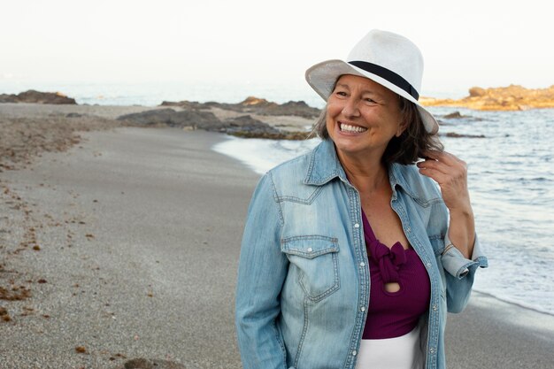 Donna anziana sorridente in spiaggia che si gode la giornata