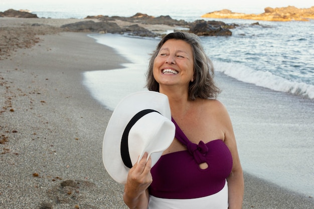 Donna anziana sorridente in spiaggia che si gode la giornata