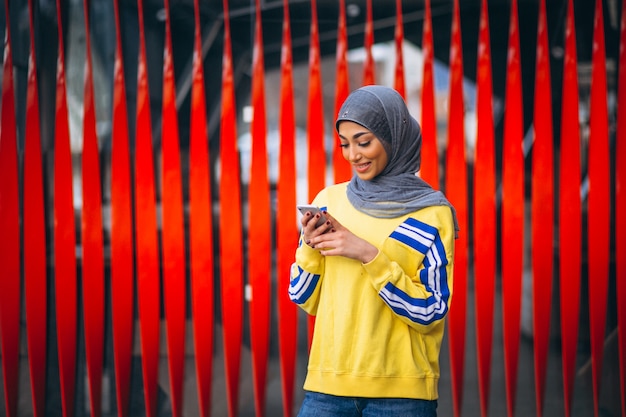 Donna araba nel ouside del hijab nella via facendo uso del telefono