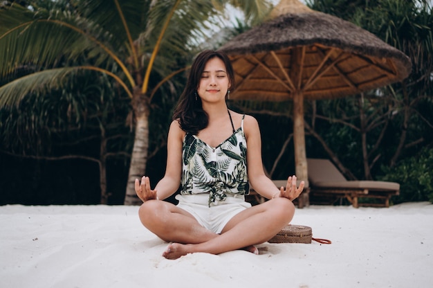 Donna asiatica allo yoga di pratica della spiaggia