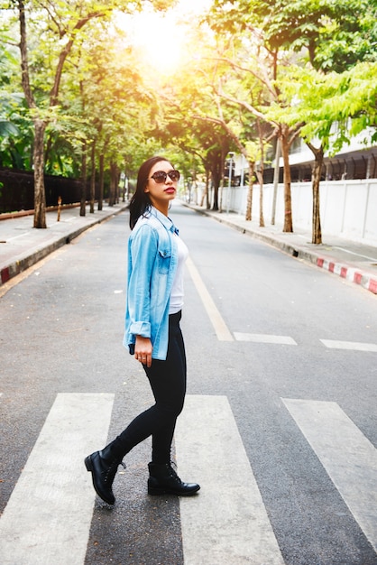 Donna asiatica che cammina attraversando la strada