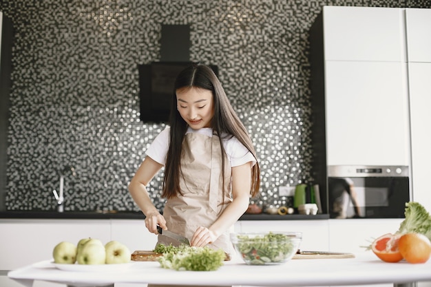 Donna asiatica che cucina a casa.