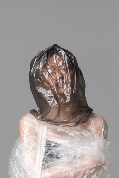 Donna asiatica che è coperta in sacchetti di plastica