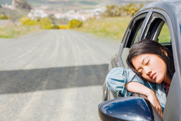 Donna asiatica che fa un sonnellino in automobile durante il roadtrip