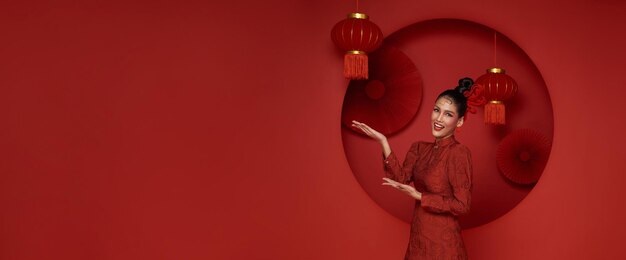 Donna asiatica che indossa il tradizionale cheongsam qipao con il gesto di benvenuto al nuovo anno cinese 2024