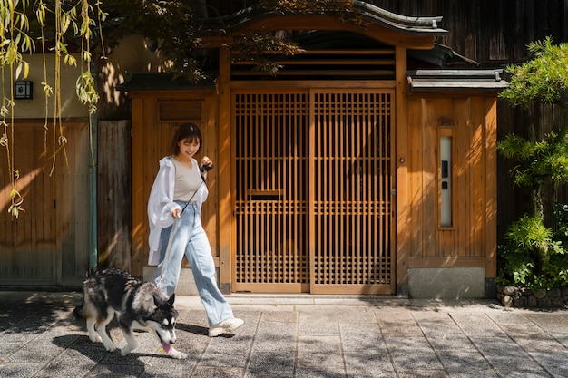 Donna asiatica che porta a spasso il suo cane husky all'aperto