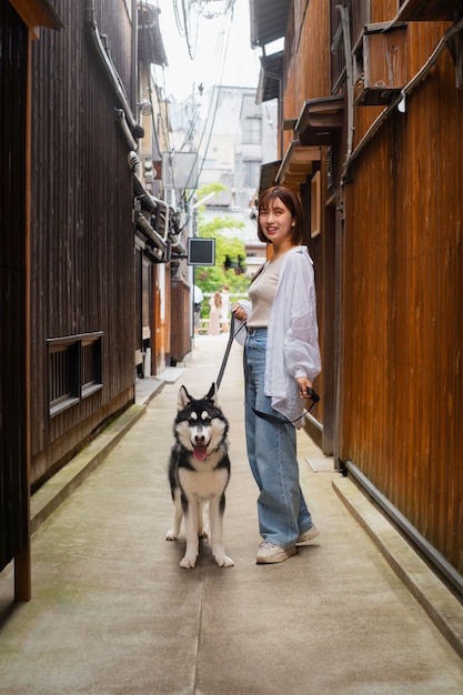 Donna asiatica che porta a spasso il suo cane husky all'aperto