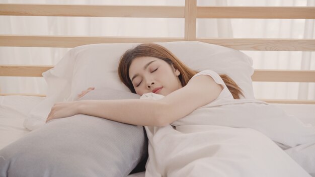 Donna asiatica che sogna mentre dormendo sul letto in camera da letto