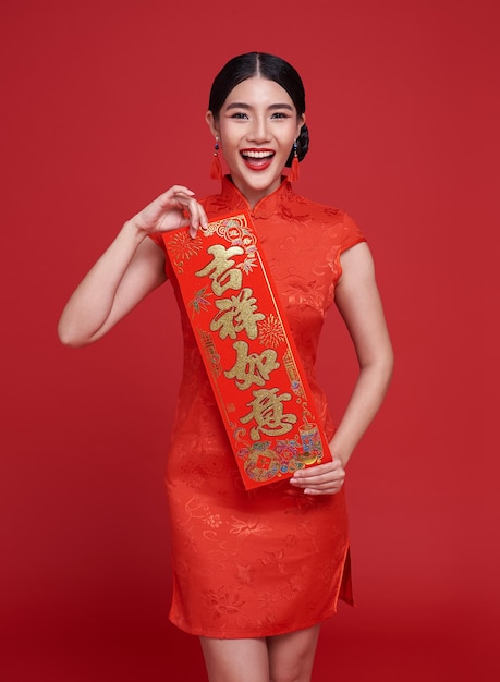 Donna asiatica che tiene distici di capodanno cinese isolati su sfondo rosso