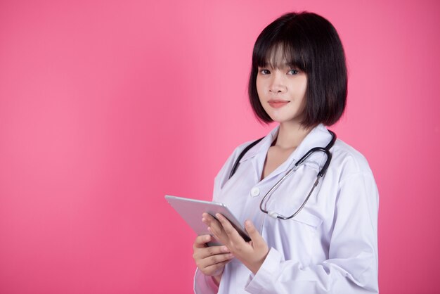 donna asiatica del medico con il camice bianco sopra il rosa