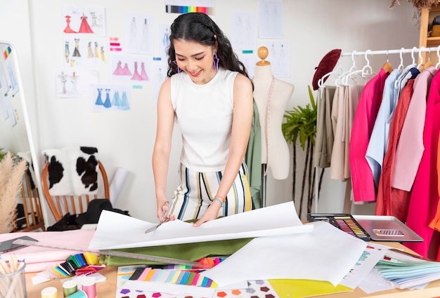 Donna asiatica del sarto che lavora sui vestiti nell'atelier di sartoria