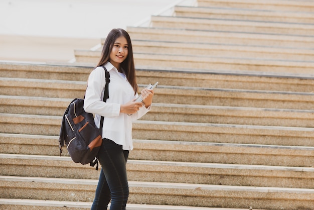 Donna asiatica dello studente con il computer portatile e la borsa, concetto di formazione