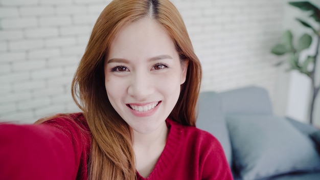 Donna asiatica di blogger che utilizza lo smartphone che registra video del video del vlog in salone a casa