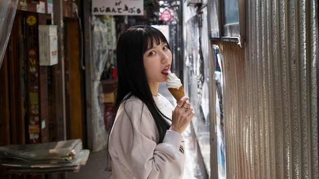 Donna asiatica di vista laterale che lecca il cono gelato