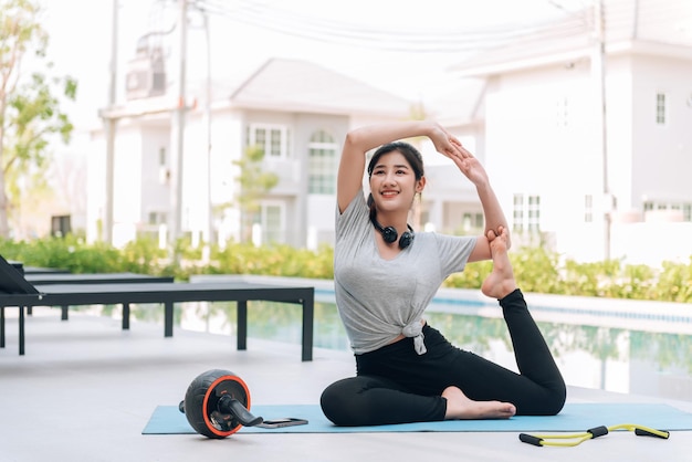 Donna asiatica felice che allunga esercizio e allenamento yoga al mattino a casa all'aperto