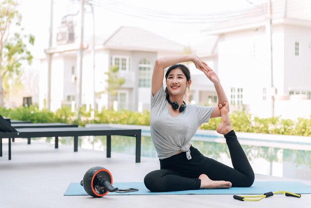 Donna asiatica felice che allunga esercizio e allenamento yoga al mattino a casa all'aperto