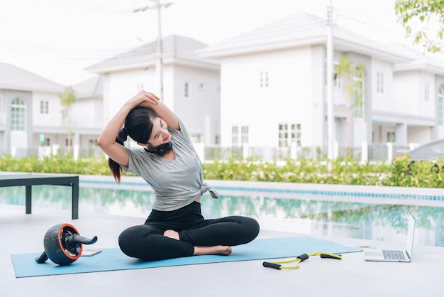 Donna asiatica felice che allunga esercizio e allenamento yoga al mattino a casa