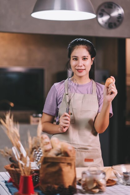 Donna asiatica felice che cucina prodotti da forno fatti in casa a casa Avviare il concetto di piccola impresa di PMI