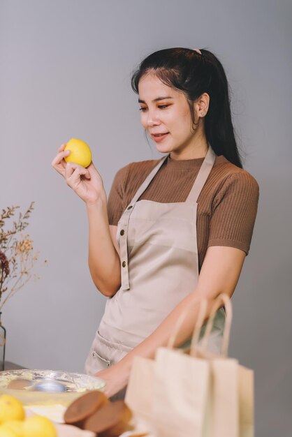 Donna asiatica felice che cucina prodotti da forno fatti in casa a casa Avviare il concetto di piccola impresa di PMI