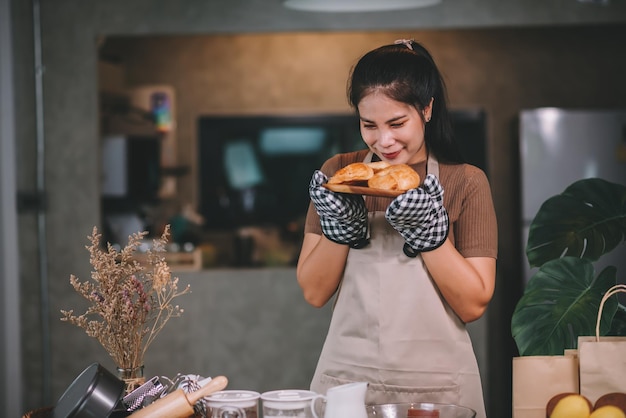 Donna asiatica felice che cucina prodotti da forno fatti in casa a casa Avviare il concetto di piccola impresa di PMI