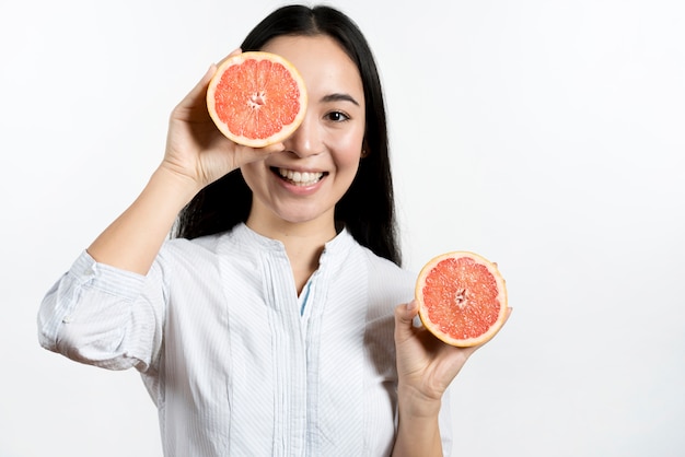 Donna asiatica sorridente che fa fronte divertente sopra fondo bianco