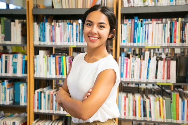 Donna asiatica sorridente che posa alla biblioteca pubblica