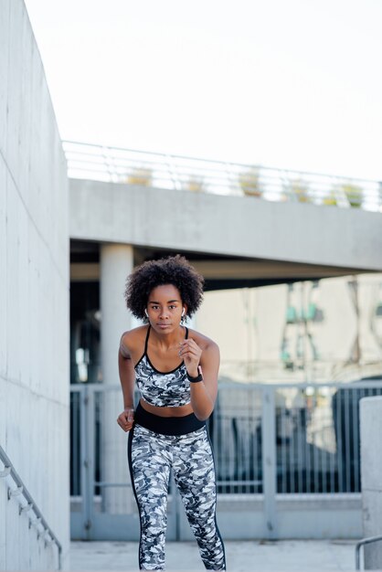 Donna atletica afro in esecuzione e facendo esercizio all'aperto