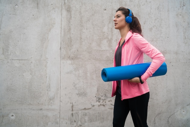 Donna atletica che tiene una stuoia di addestramento.