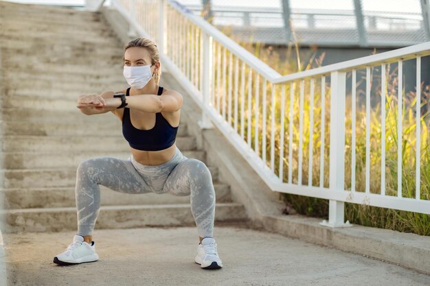 Donna atletica con maschera facciale che esercita squat all'aperto