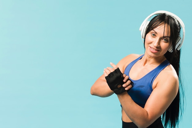 Donna atletica nell'usura della palestra che posa con le cuffie