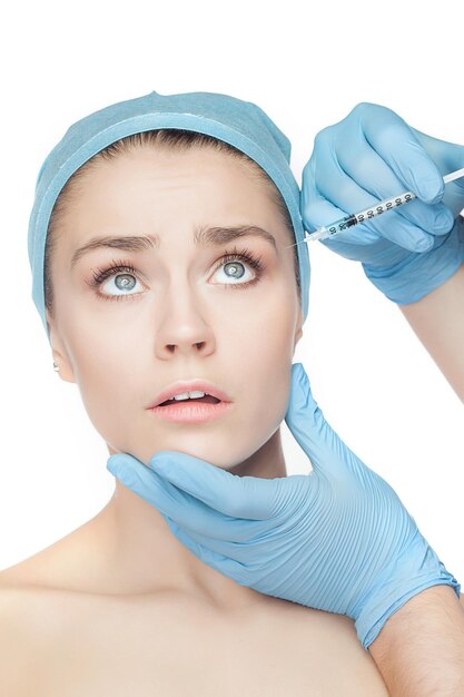 Donna attraente alla chirurgia plastica con una siringa in faccia