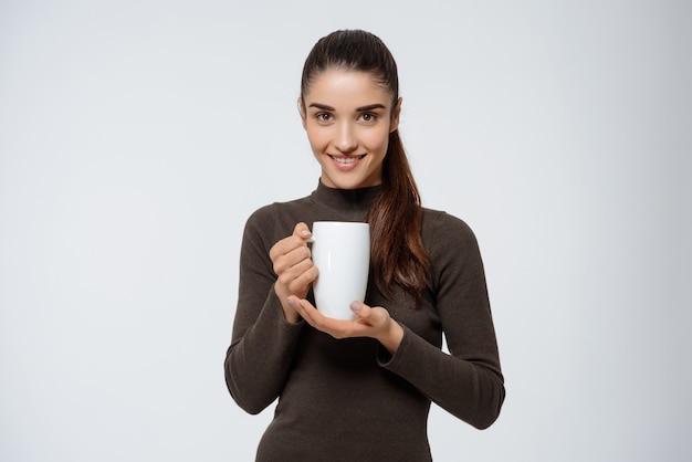 Donna attraente che beve tè, tenendo la tazza