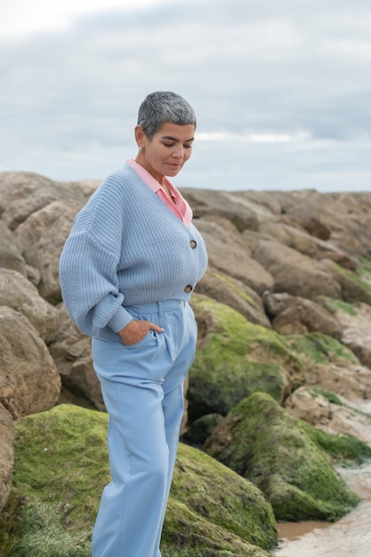 Donna attraente che cammina vicino al mare. Modello femminile con capelli corti che cammina in una giornata nuvolosa. Natura, concetto di tempo libero