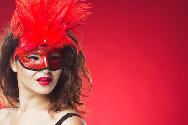 Donna attraente che posa nella maschera rossa