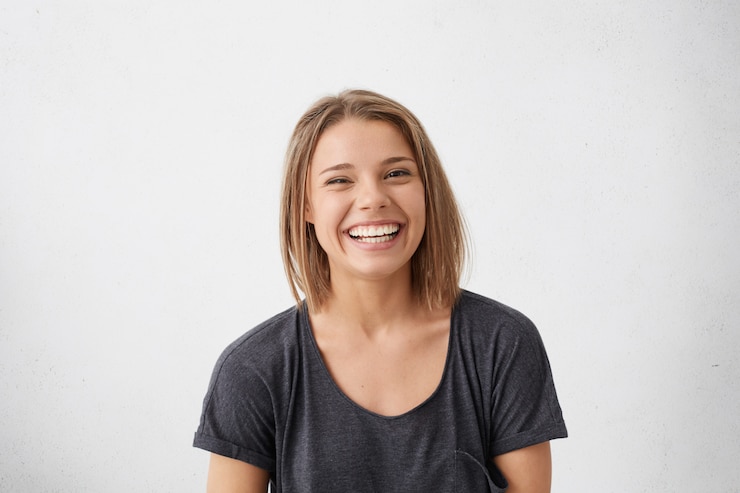 Foto gratuito donna attraente con i capelli corti biondi che è molto felice di sorridere con un ampio sorriso che mostra i suoi denti perfetti divertendosi al chiuso. gioiosa donna allegra eccitata che si rallegra