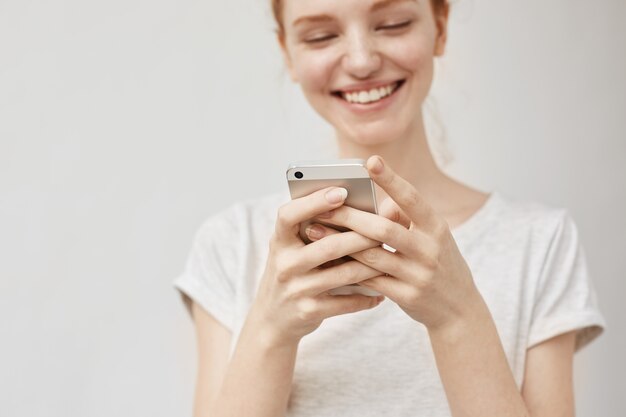 Donna attraente di redhead che osserva sorridere del telefono di AR.