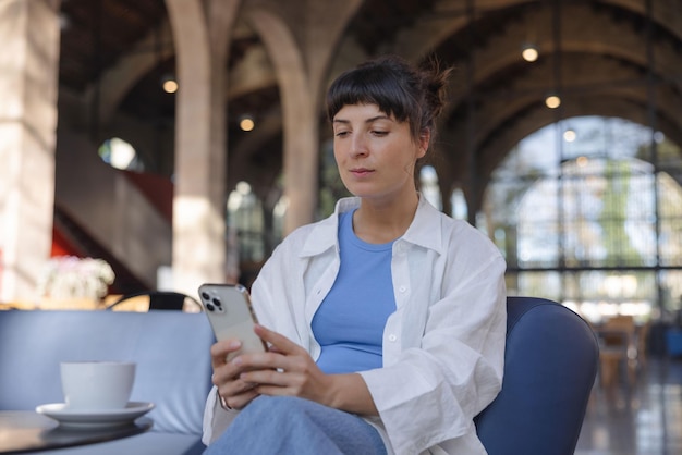 Donna attraente nel telefono della holding del caffè