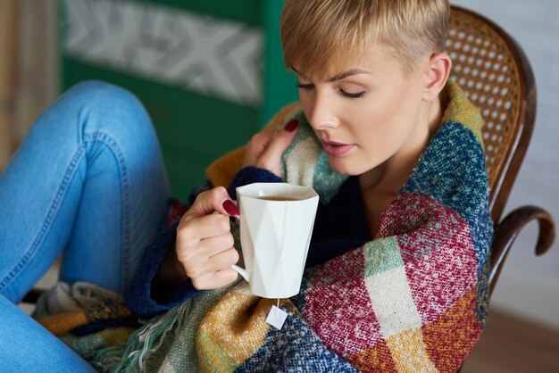 Donna avvolta in una coperta che beve tè in una giornata invernale