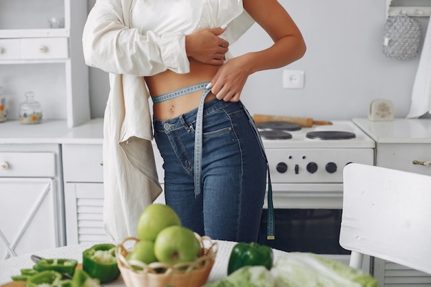 Donna bella e sportiva in una cucina con verdure