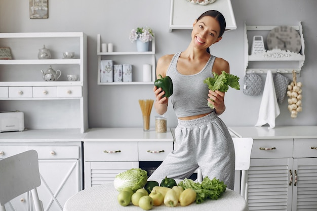 Donna bella e sportiva in una cucina con verdure