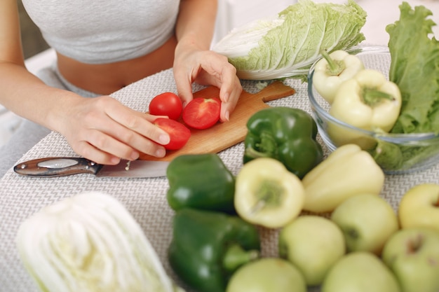 Donna bella e sportiva in una cucina con verdure