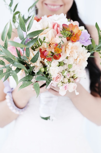 Donna bella sposa in abito da sposa che tiene un mazzo di fiori