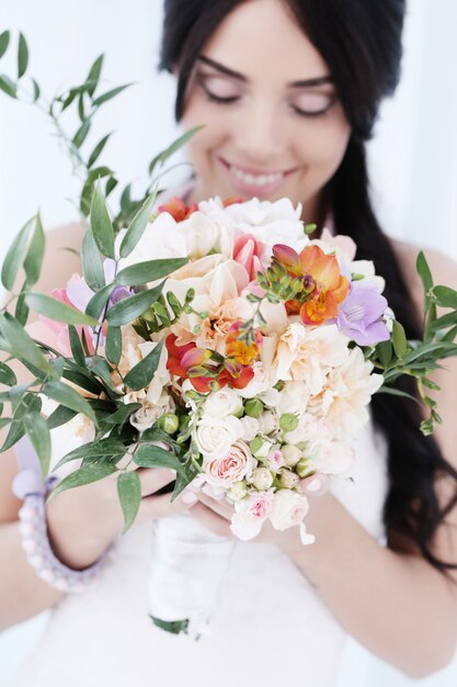 Donna bella sposa in abito da sposa che tiene un mazzo di fiori