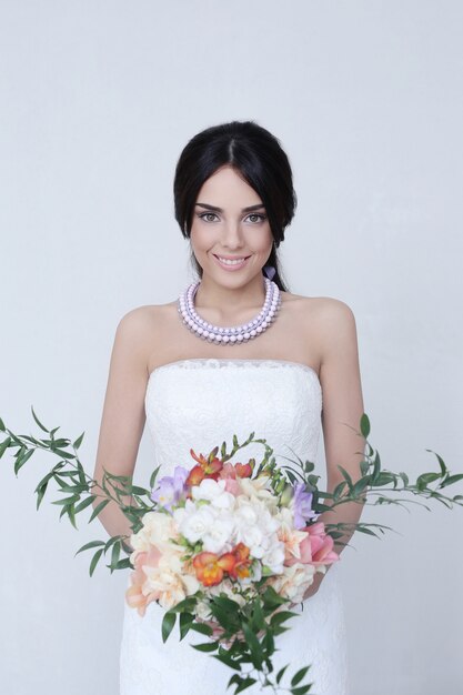 Donna bella sposa in abito da sposa che tiene un mazzo di fiori